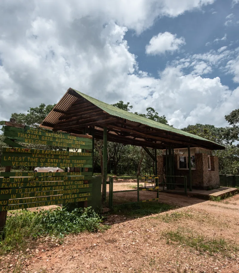 Thazima Gate entrance to Nyika National Park with a wooden gatehouse and park information sign